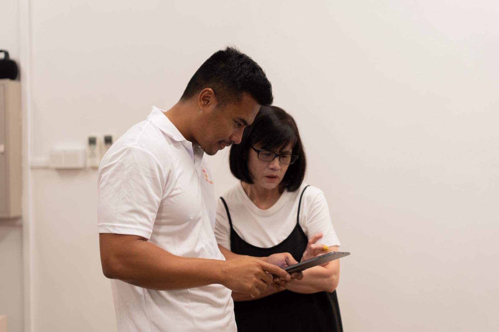 A Fit Kaki coach walking a senior through her programme notes at the studio